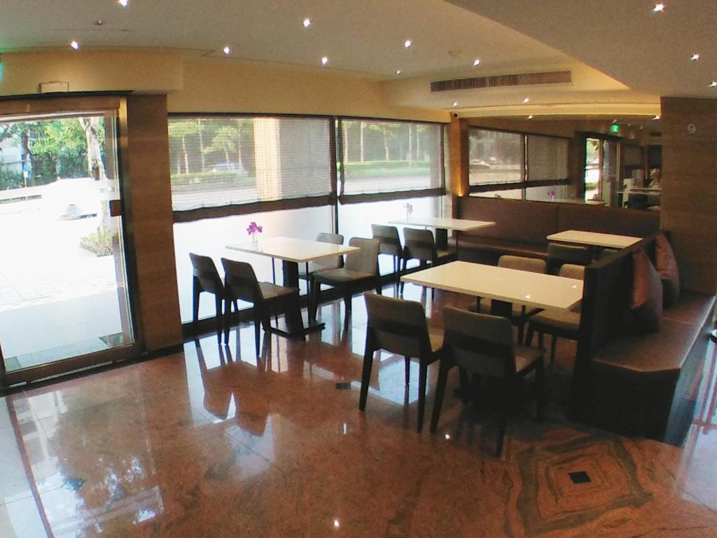 a restaurant with tables and chairs in a room with windows at KDM Hotel in Taipei