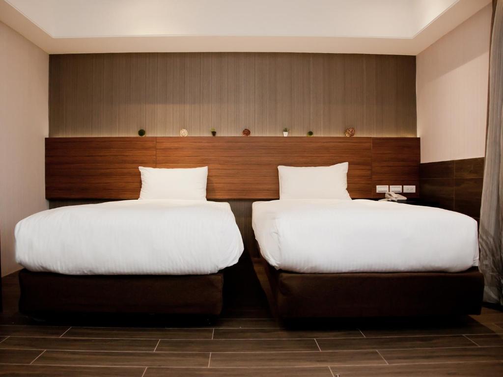 two beds sitting next to each other in a room at KDM Hotel in Taipei