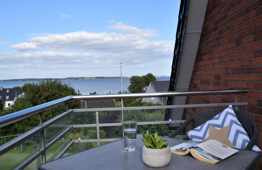 a table on a balcony with a view of the water at Ostsehbutzen in Glücksburg