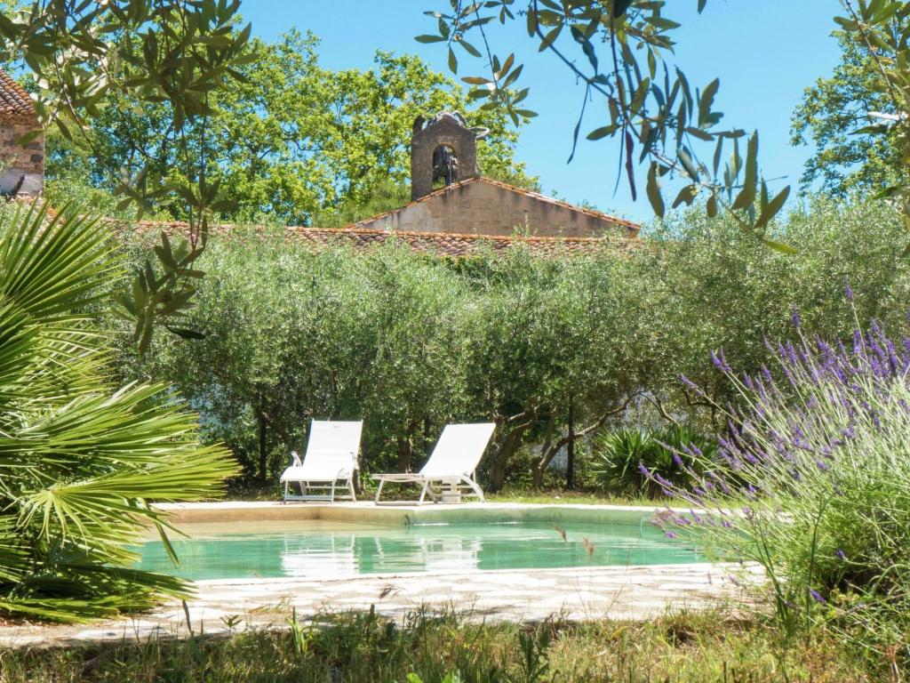 twee witte stoelen naast een zwembad bij Beautiful holiday home with pool in Autignac