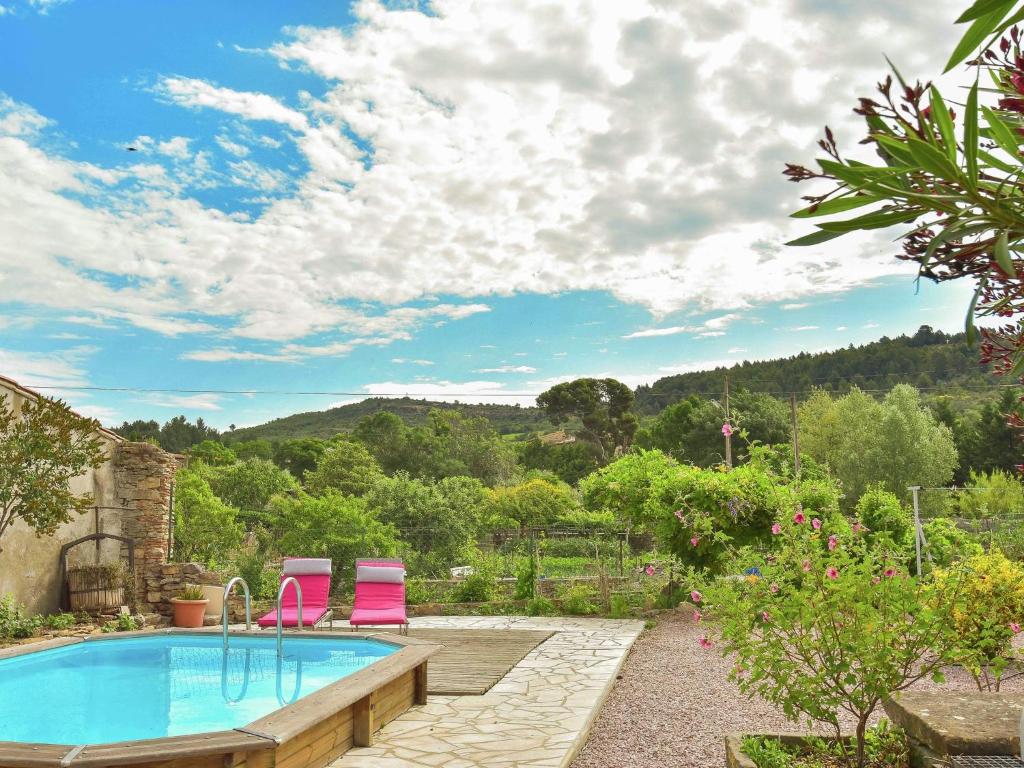 a swimming pool with two pink chairs in a garden at Holiday home with swimming pool in Félines-Minervois