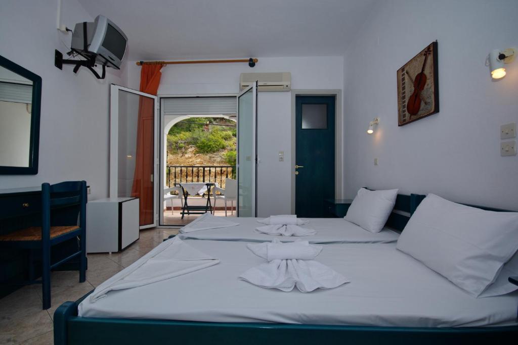 a bedroom with a large white bed and a balcony at Studios Nelli Alonissos in Patitiri