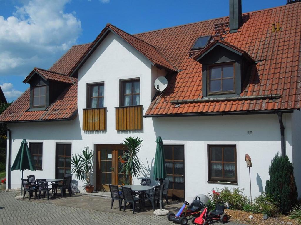 a white house with a table and chairs at Ferienwohnung Scherr in Neunburg vorm Wald