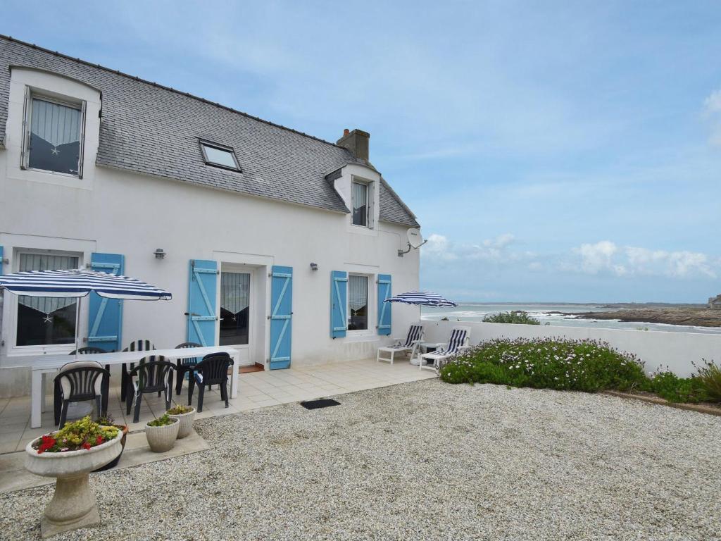 een wit huis met een tafel en stoelen en de oceaan bij Beautiful holiday home by the sea in Penmarch in Saint-Guénolé
