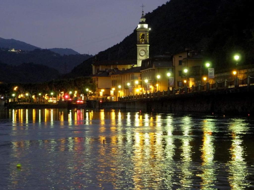 Una ciudad con una torre de reloj y un río por la noche en Al ponte vecchio, en San Pellegrino Terme