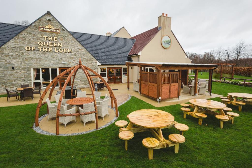 um pátio exterior com mesas e cadeiras e um parque infantil em Queen of the Loch, Balloch by Marston's Inns em Balloch