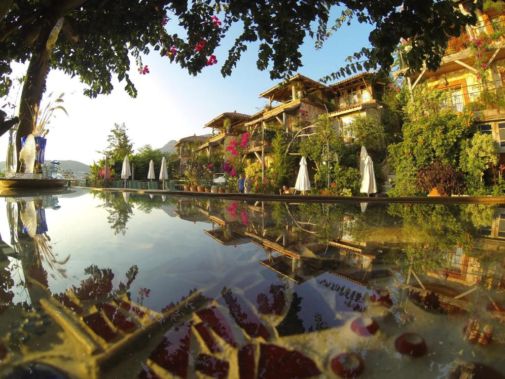 a pool of water with umbrellas and a building at Fidanka Hotel in Kalkan