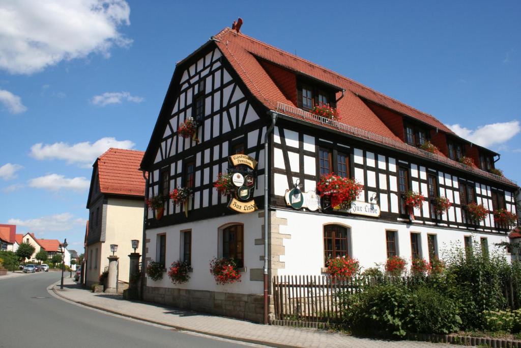 un edificio blanco y negro al lado de una calle en Gasthaus & Hotel Zur Linde, en Hermsdorf