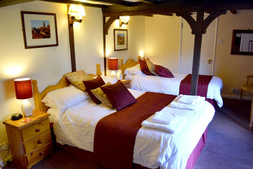 a bedroom with two beds and a night stand with two lamps at The Bull's Head Inn in Bridgnorth