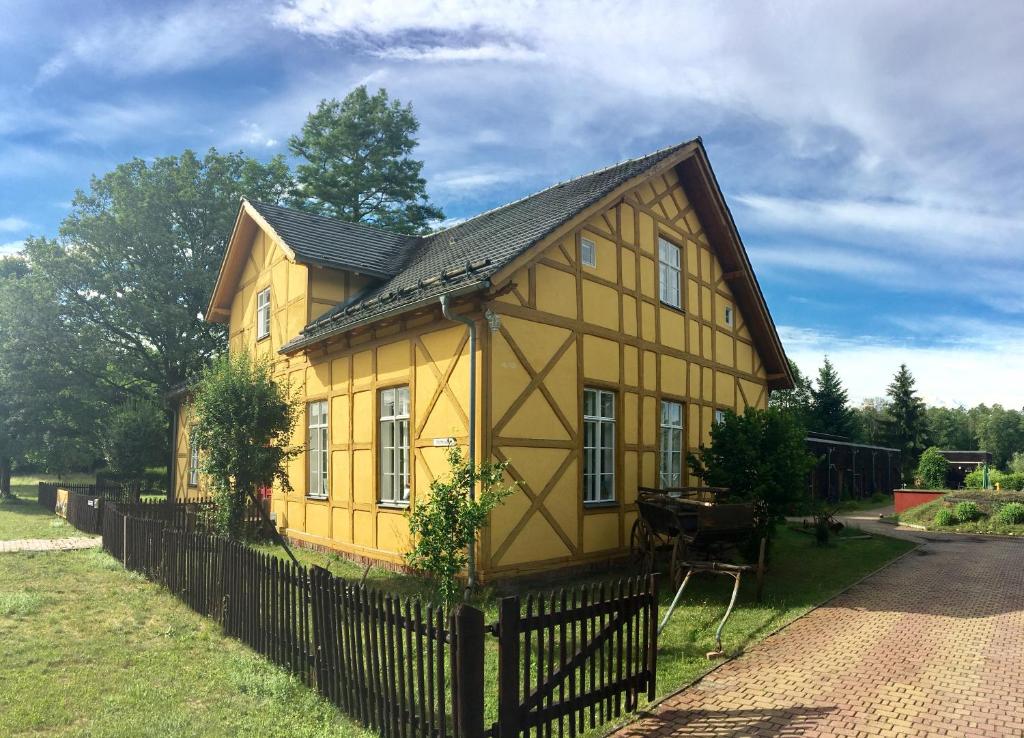 a small yellow house with a black fence at Museumsherberge Glashütte in Baruth