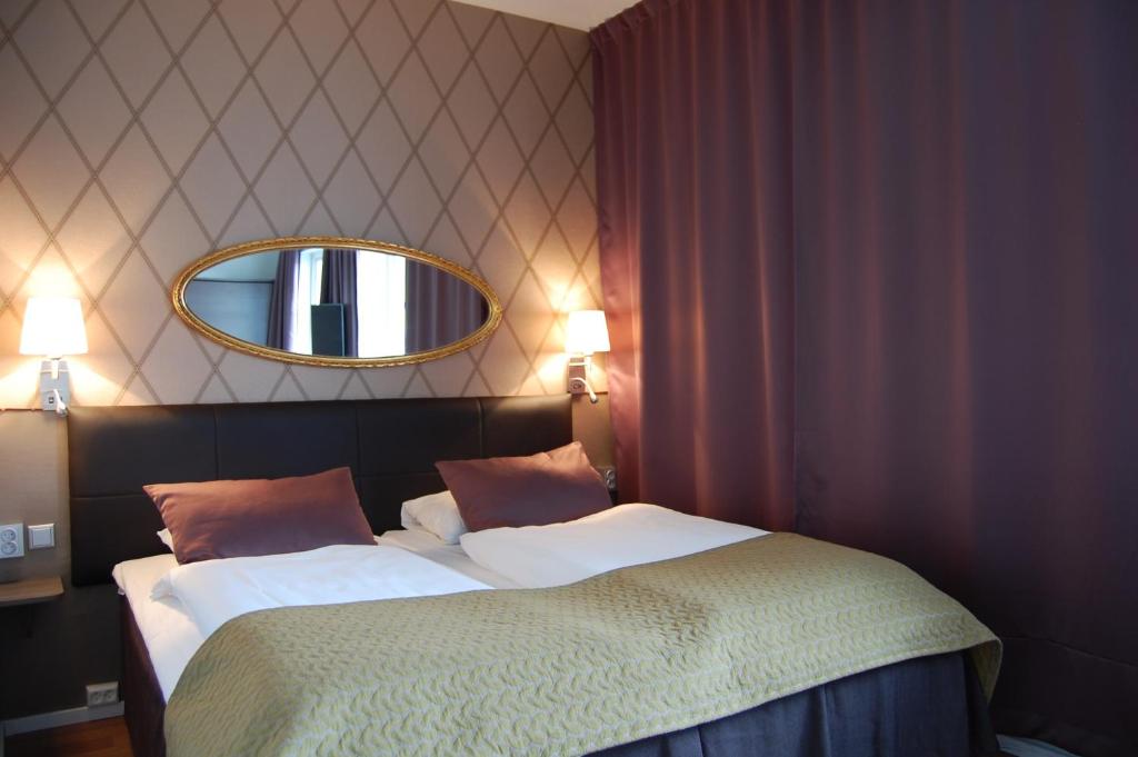 a bedroom with two beds with a mirror on the wall at Thon PartnerHotel Skagen in Bodø