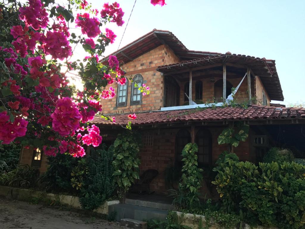 una casa con fiori rosa di fronte di Pousada Santa Bárbara a Marudá