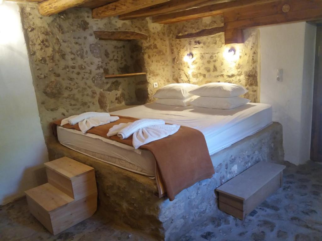 ein Schlafzimmer mit einem Bett in einer Steinmauer in der Unterkunft Heracles Traditional Cretan Houses in Spílion