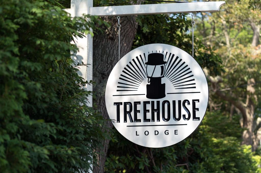 una señal para una cabaña en el árbol colgando de un árbol en Treehouse Lodge, en Woods Hole