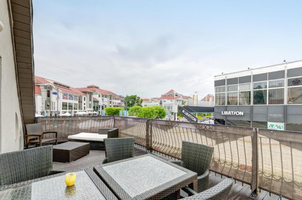 a balcony with tables and chairs and a view of a train at Dom & House – Apartments Port Monte Cassino in Sopot