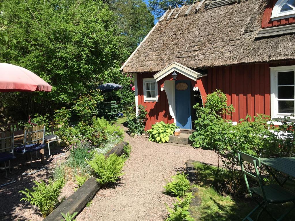 uma casa vermelha com telhado de palha e um jardim em Malistorpets Rosor em Varberg