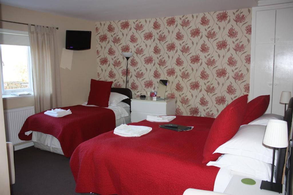 a hotel room with two beds with red sheets at Red Lion Inn in Newbrough