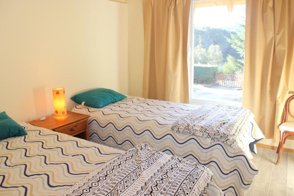 2 Betten in einem Zimmer mit Fenster in der Unterkunft El Arrayan in Villa Pehuenia
