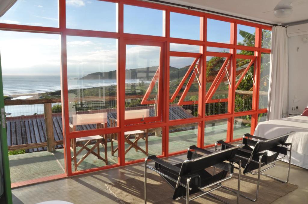 a bedroom with a large window with a view of the ocean at Pousada Pedra Grande in Praia do Rosa