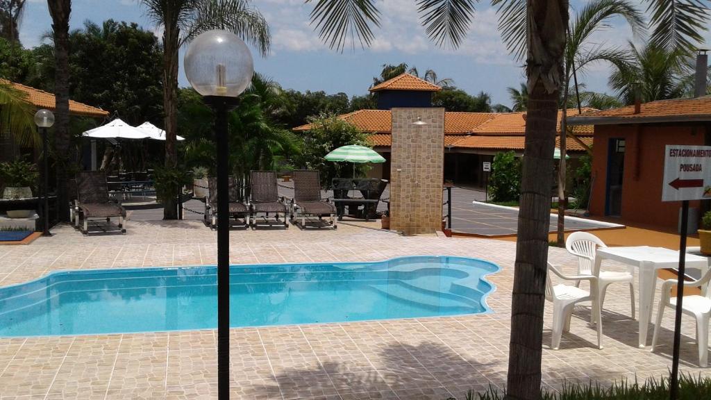 a pool with a table and chairs and a lamp at Pousada Recanto Solar dos Pássaros in Olímpia