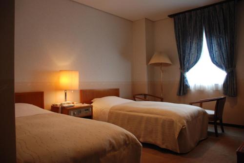 pokój hotelowy z 2 łóżkami i oknem w obiekcie Kojima Puchi Hotel w mieście Kurashiki
