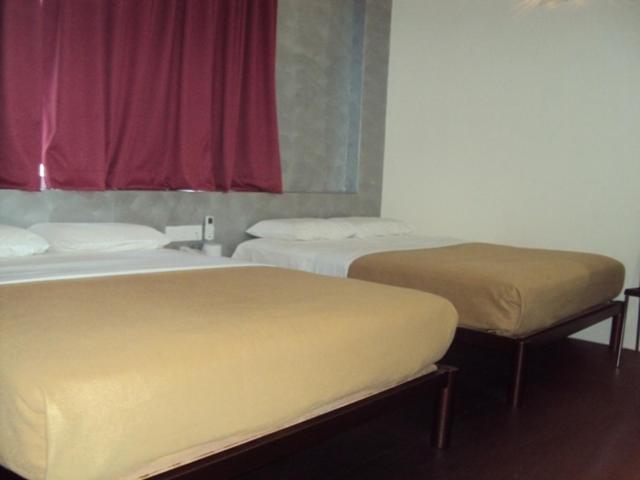 Habitación con 2 camas y ventana roja. en Tai Pan Hotel, en Kuching