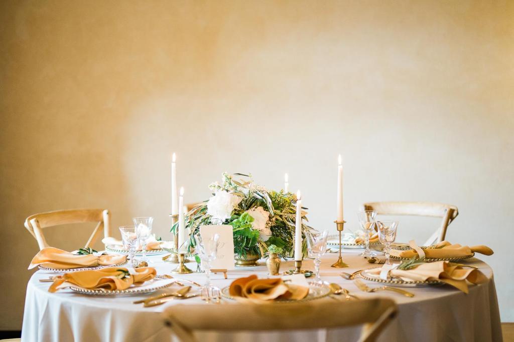 Round banquet table elegantly set with white linen, candles and floral centerpiece