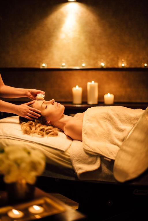 Woman receiving relaxing facial massage on treatment bed, candlelit spa ambiance