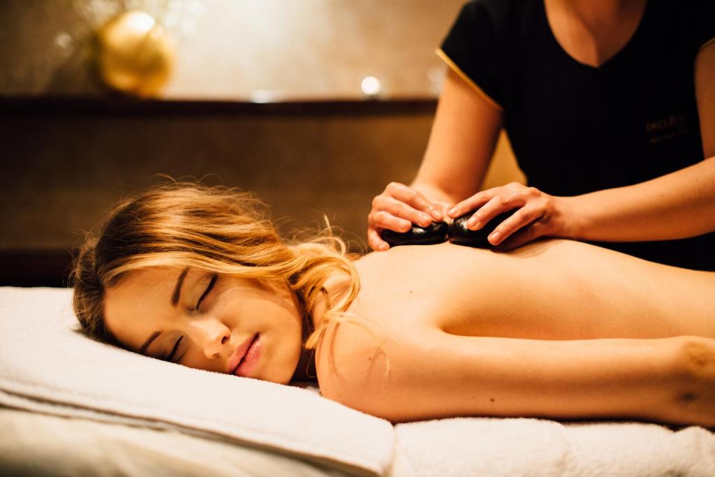 Relaxed woman receiving hot stone back massage in warm, dimly lit spa room