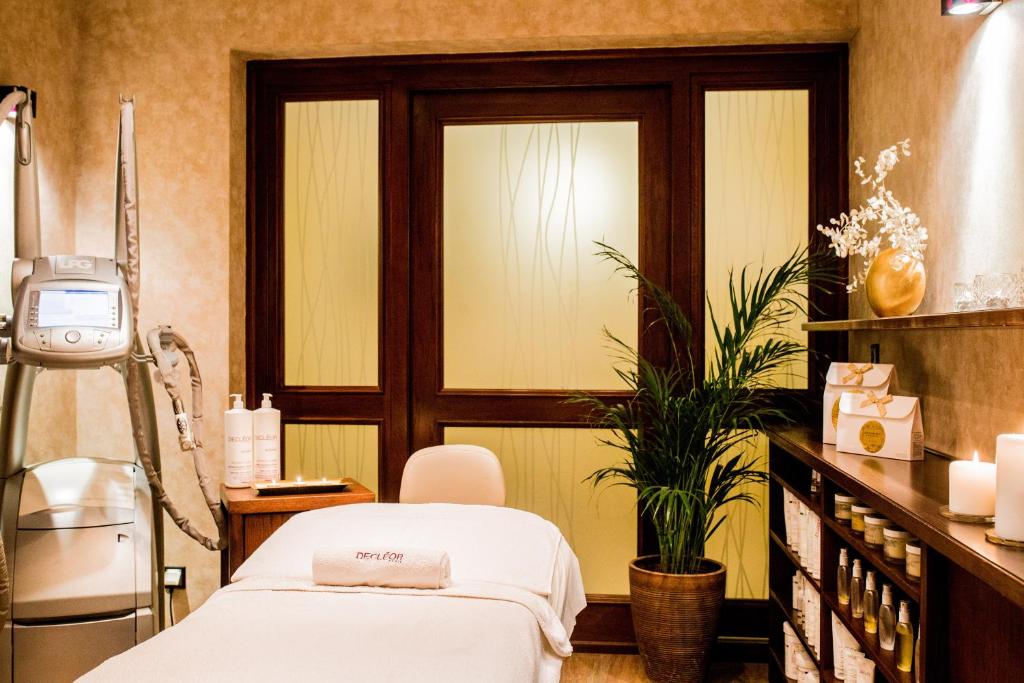 massage table in cozy spa room with treatment machine, potted plant, candles, warm lighting