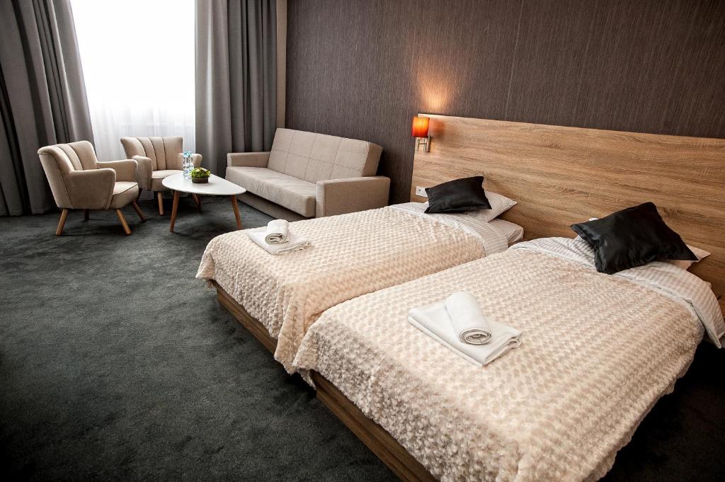 een hotelkamer met 2 bedden en een stoel bij Elba Hotel in Ostrołęka