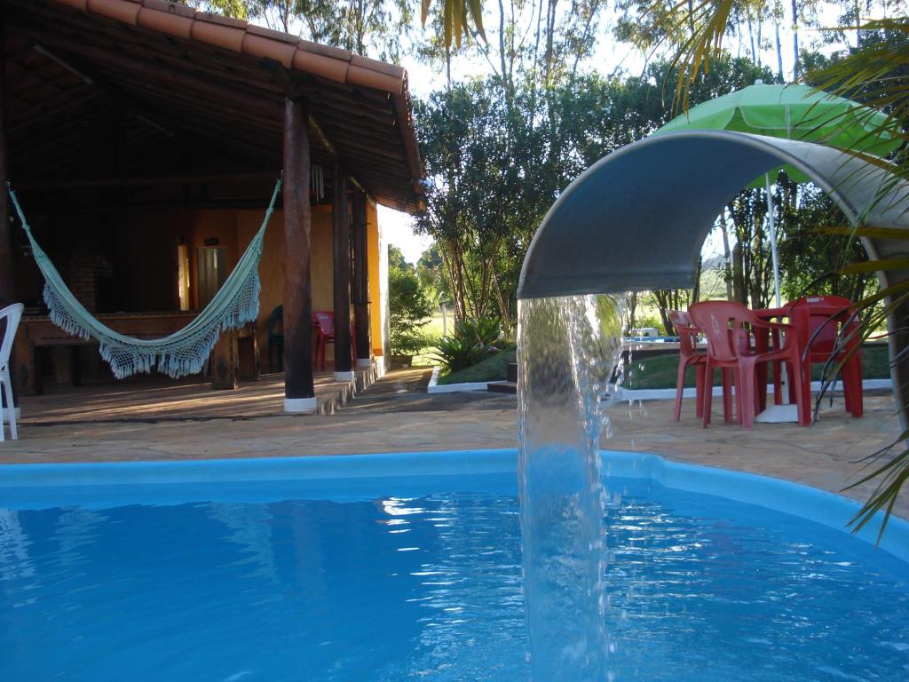 a water fountain in a pool next to a house at Hotel da Lagoa in Curvelo