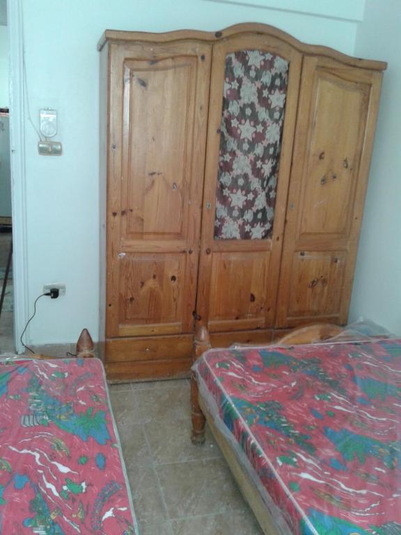 ein Schlafzimmer mit einem Holzschrank und einem Bett in der Unterkunft شقة شاطيء النخيل -بالما كورت in Alexandria
