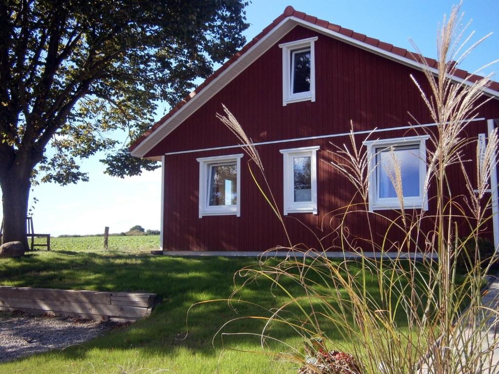 a red house with a tree and grass at Lindhus Grödersby in Grödersby