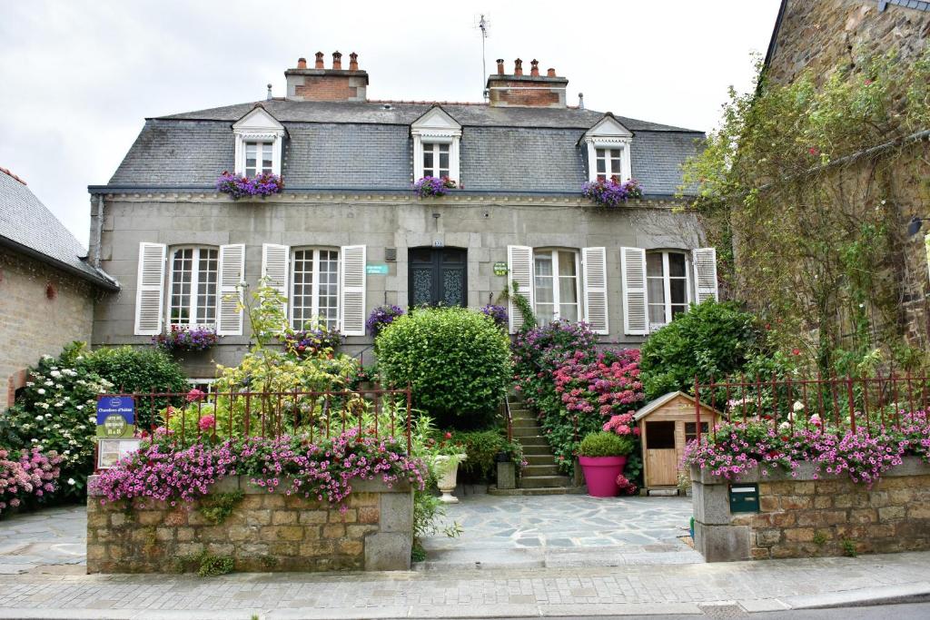 uma casa velha com flores em frente em Chambres d'Hôtes l'Hermine em Val Couesnon