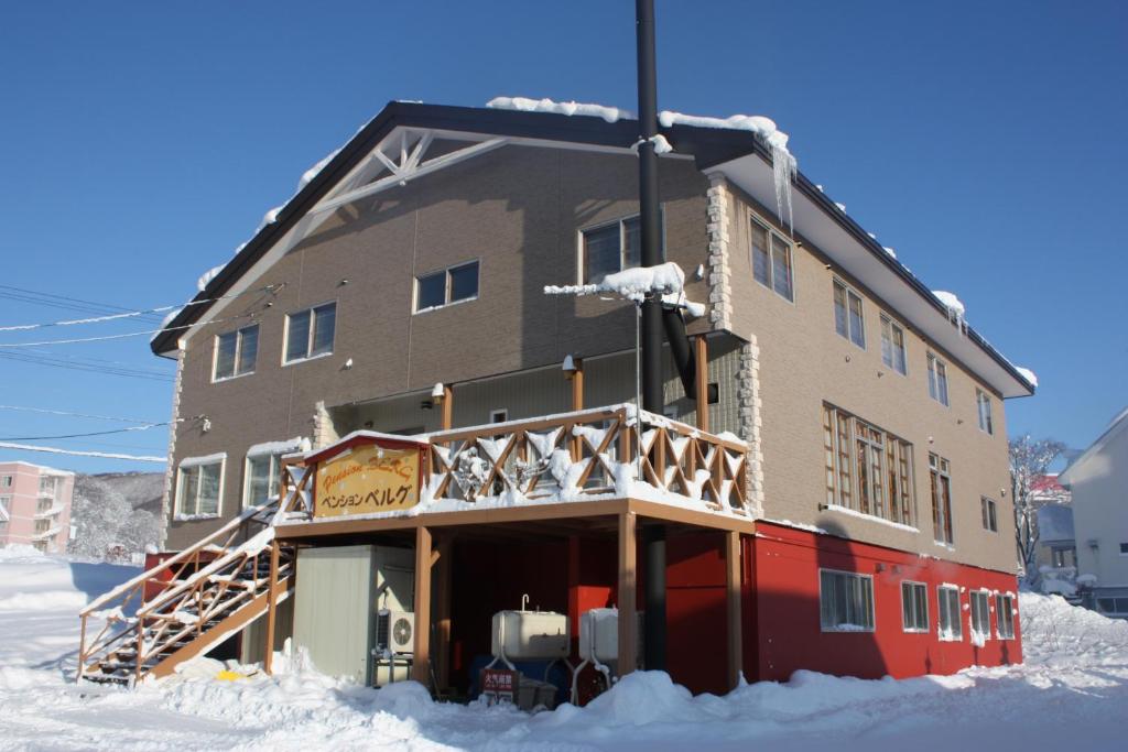 un gran edificio en la nieve con nieve alrededor en Pension Berg, en Niseko