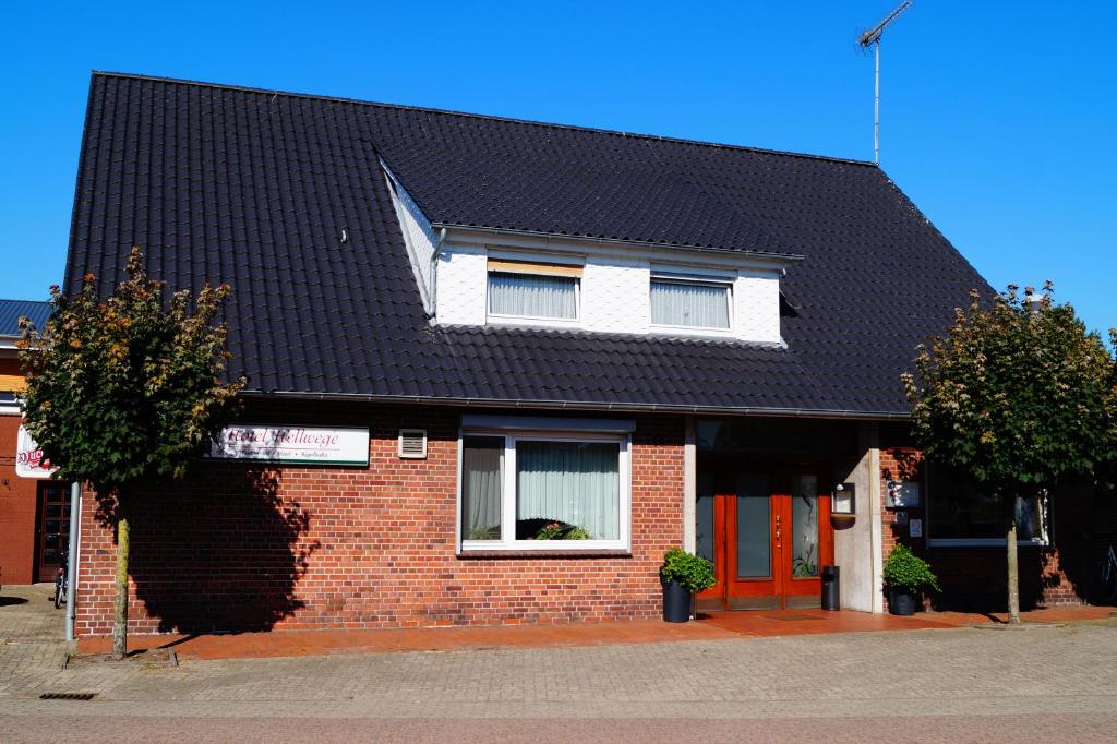 a red brick house with a black roof at Hotel Hellwege in Himmelpforten