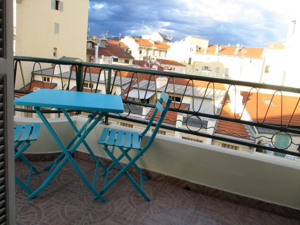 une table bleue et des chaises assises sur un balcon dans l'établissement Appartamento in rue Halevy, à Nice