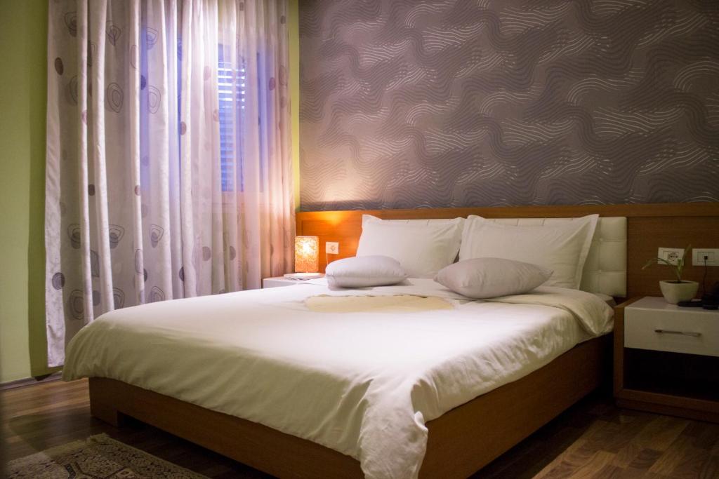 un letto con lenzuola e cuscini bianchi in una camera da letto di Hotel Bylis a Tirana