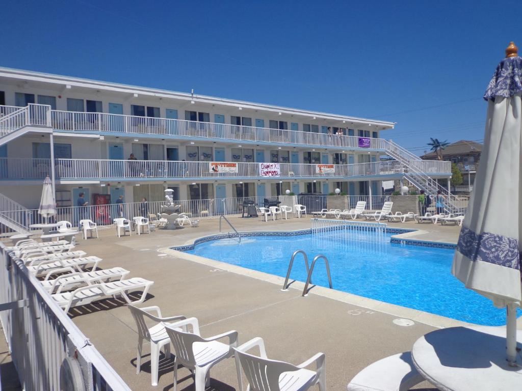un hotel con piscina, sillas y un edificio en Caprice Motel - Wildwood, en Wildwood
