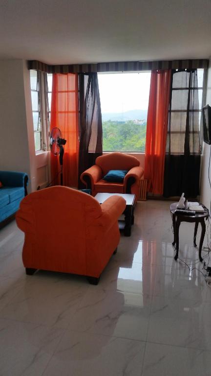 a living room with orange furniture and a large window at Malia's New Kgn Apartment in Kingston