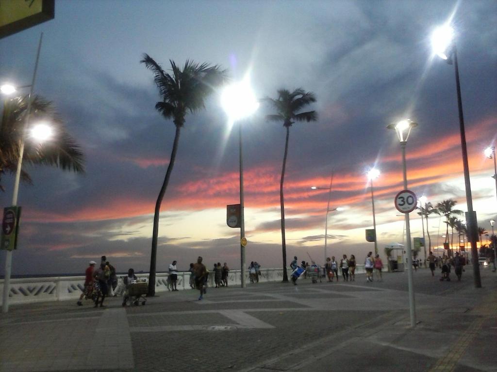 un grupo de personas caminando por una calle con palmeras en Studio na praia da Barra, en Salvador