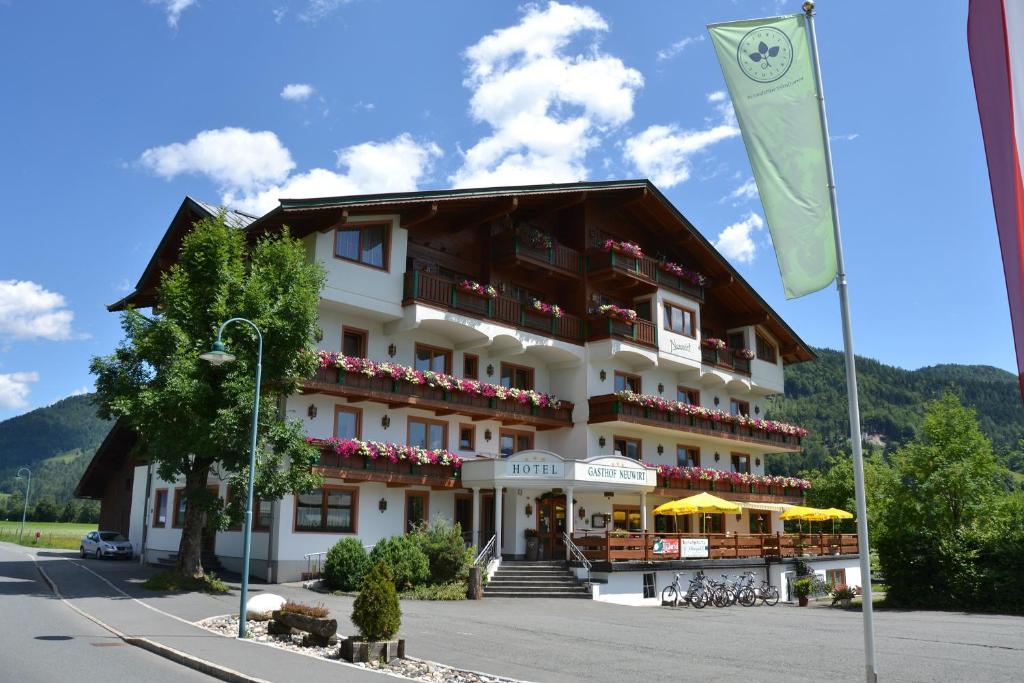 ein großes weißes Gebäude mit einer Flagge davor in der Unterkunft Hotel Neuwirt in Kirchdorf in Tirol