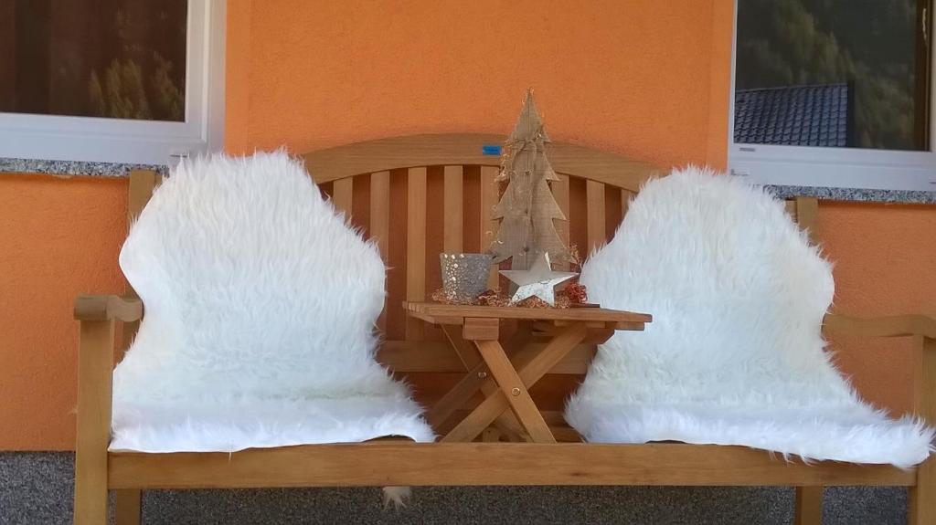 a wooden bench with white fuzzy pillows and a table at Ferienwohnung Hannes Steirer in Neustift im Stubaital