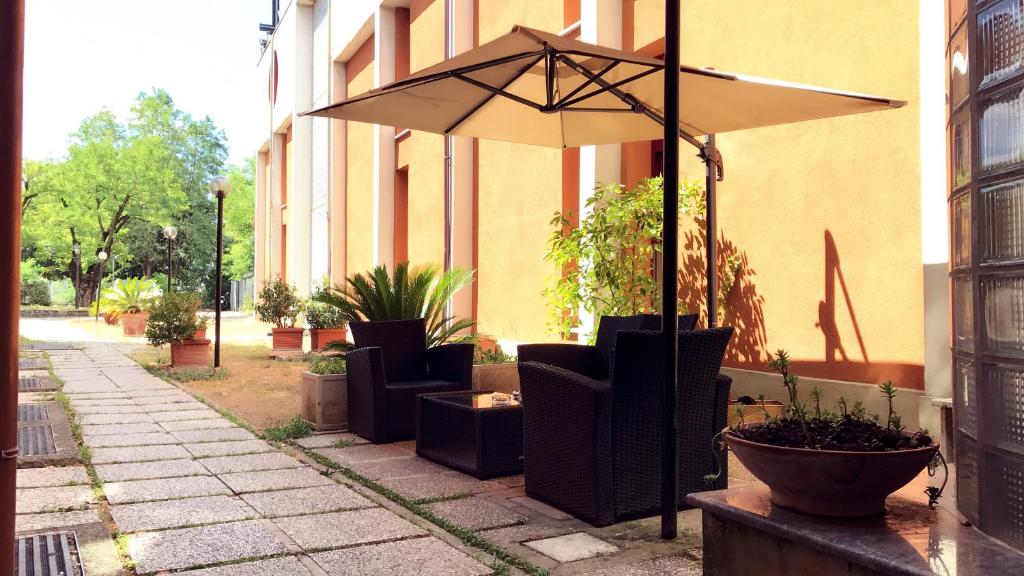 a patio with chairs and an umbrella next to a building at Hotel Maxim in Bologna
