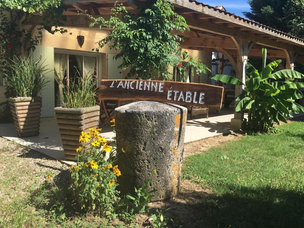 un cartello di fronte a una casa con dei fiori di "L'Ancienne Etable" Dordogne a Saint-Avit-Saint-Nazaire