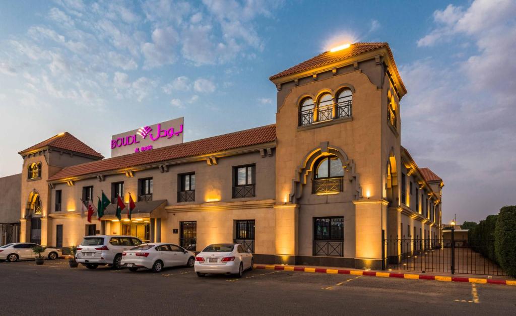 un edificio con coches estacionados frente a él en Boudl Al Rass, en Al Rass