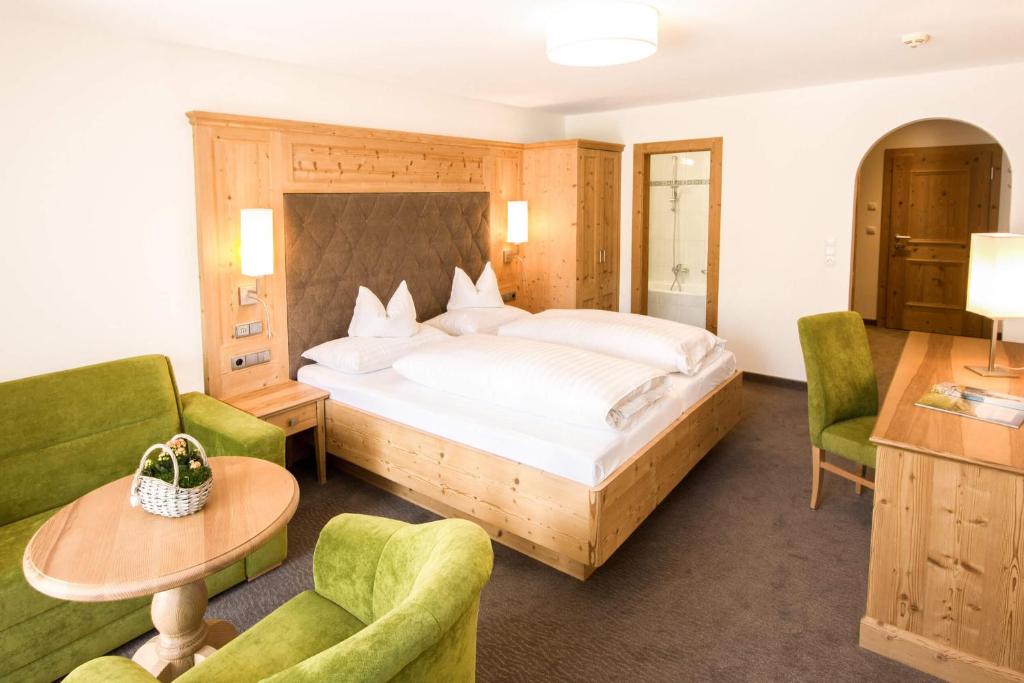 a bedroom with a bed and two green chairs at Hotel Pension Sonnleiten in Tux