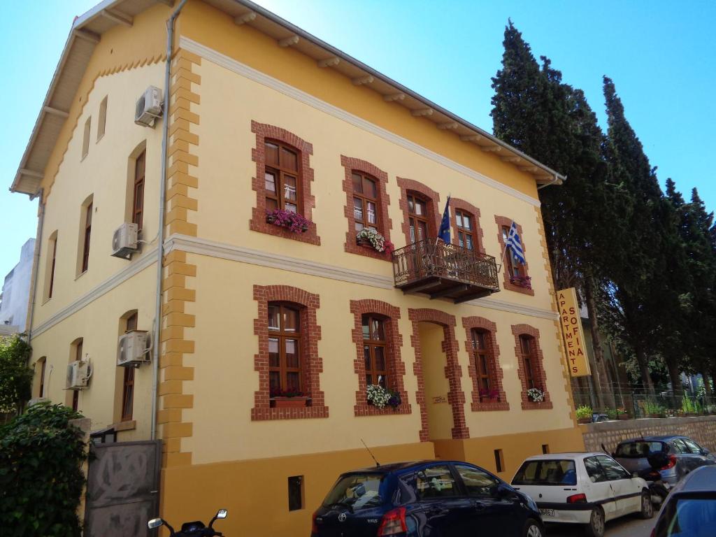 Edificio amarillo con ventanas y balcón en Sofia Apartments en Alejandrópolis