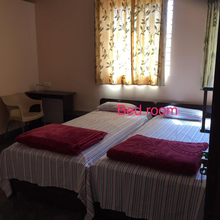 un letto con due asciugamani rossi sopra in una camera da letto di Marina Stay a Chikmagalūr